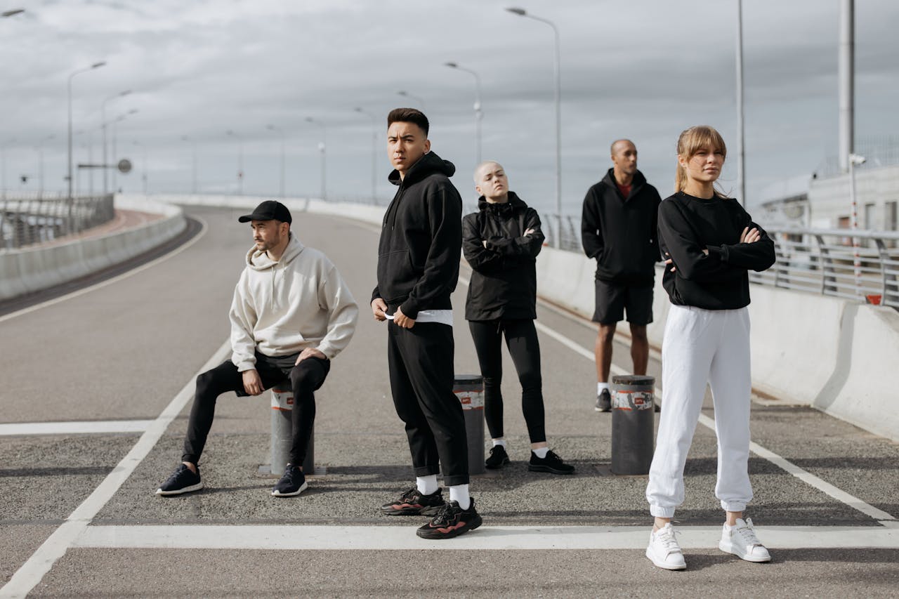 A diverse group of stylish adults posing in sportswear on an urban street.